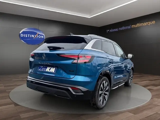 Renault Austral bleu bi-ton en 3/4 arrière droit, hayon motorisé et détails RS visibles en showroom.