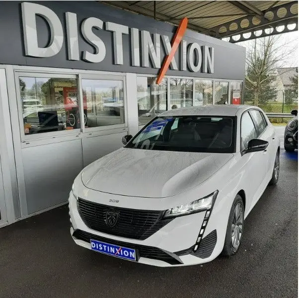 Peugeot 308 blanc banquise vue 3/4 avant droit, avec calandre noire distinctive et feux LED verticaux.