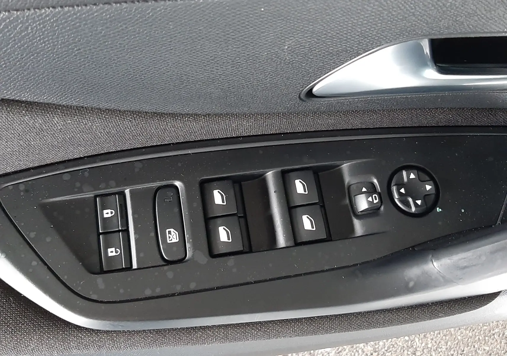 Gros plan sur les commandes de lève-vitres et rétroviseurs côté conducteur d'une Peugeot 308 blanche de 2022.