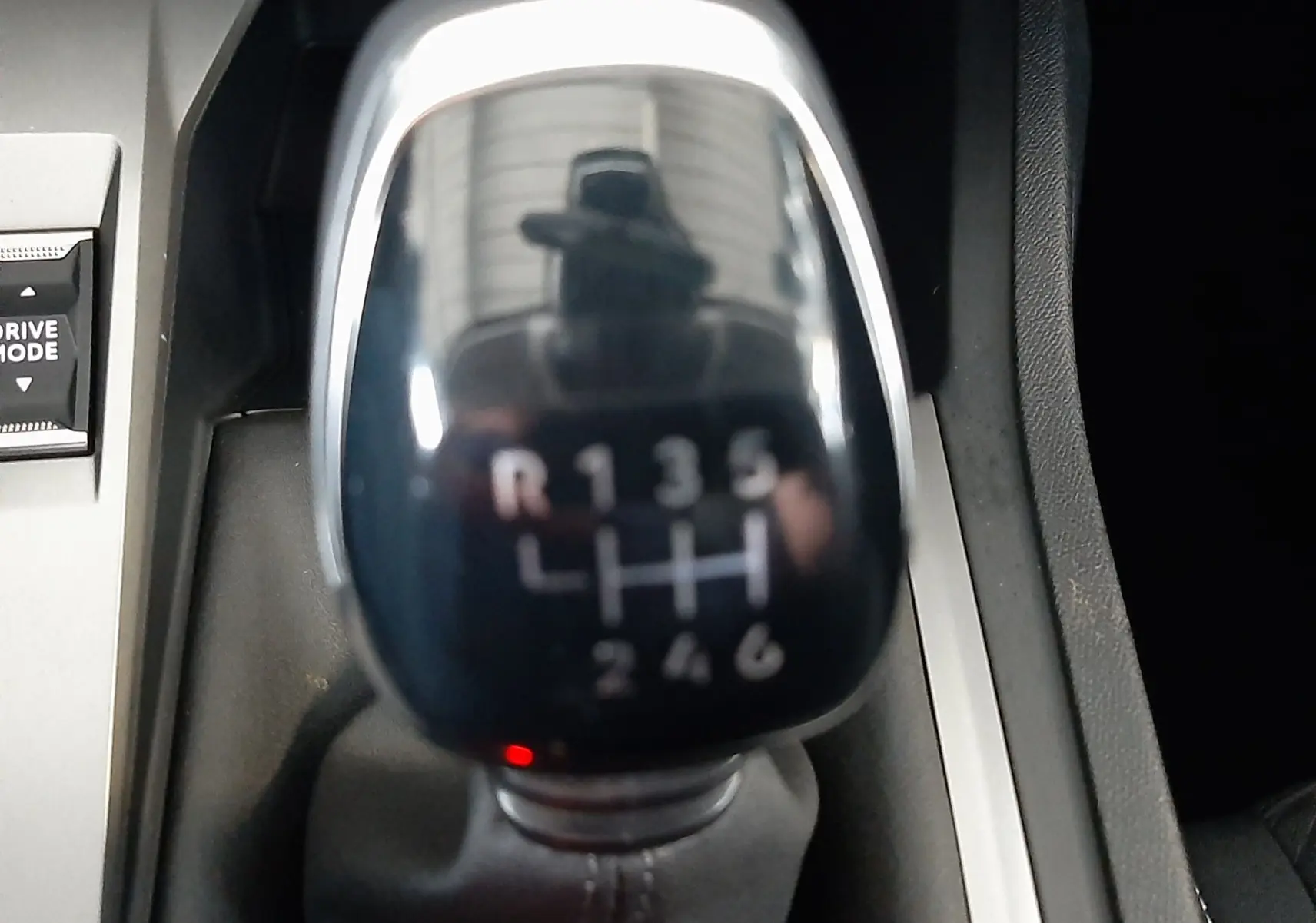 Gros plan sur le levier de vitesses manuel noir brillant de la Peugeot 308 blanche, montrant les six rapports et la marche arrière.