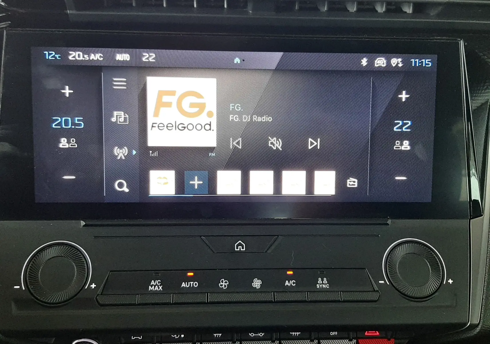 Écran tactile central du tableau de bord de la Peugeot 308 blanche, affichant la radio Feelgood en intérieur.