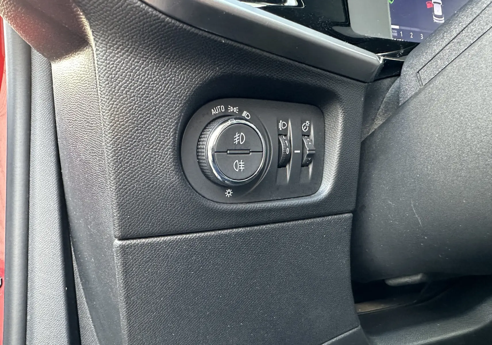 Gros plan sur le panneau de commande des phares à gauche du tableau de bord d'un Opel Mokka rouge Kardinal 2021.