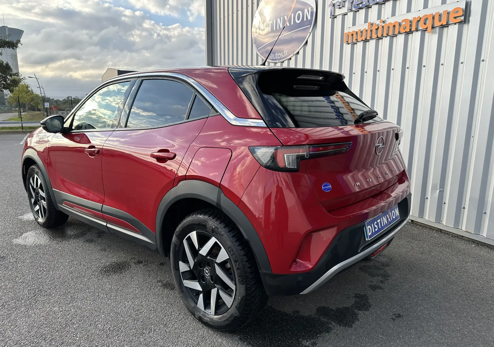 Vue 3/4 arrière droite d'un Opel Mokka rouge Kardinal 2021 avec jantes noires et toit noir brillant.