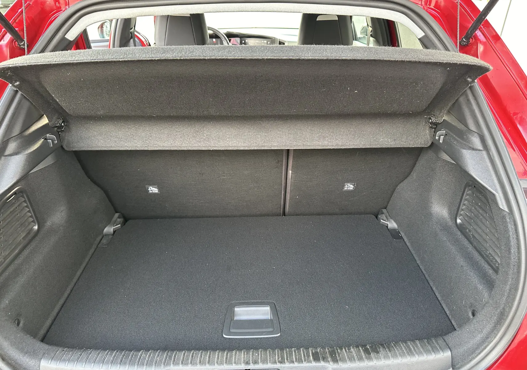 Coffre ouvert de l'Opel Mokka rouge Kardinal, vue arrière montrant un espace de chargement propre et bien agencé.