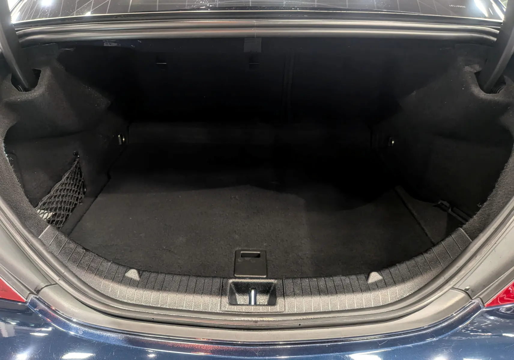 Coffre ouvert vu de l'arrière d'une Mercedes Classe CLA 200 Fascination bleu Cavansite, espace de chargement vide et propre.