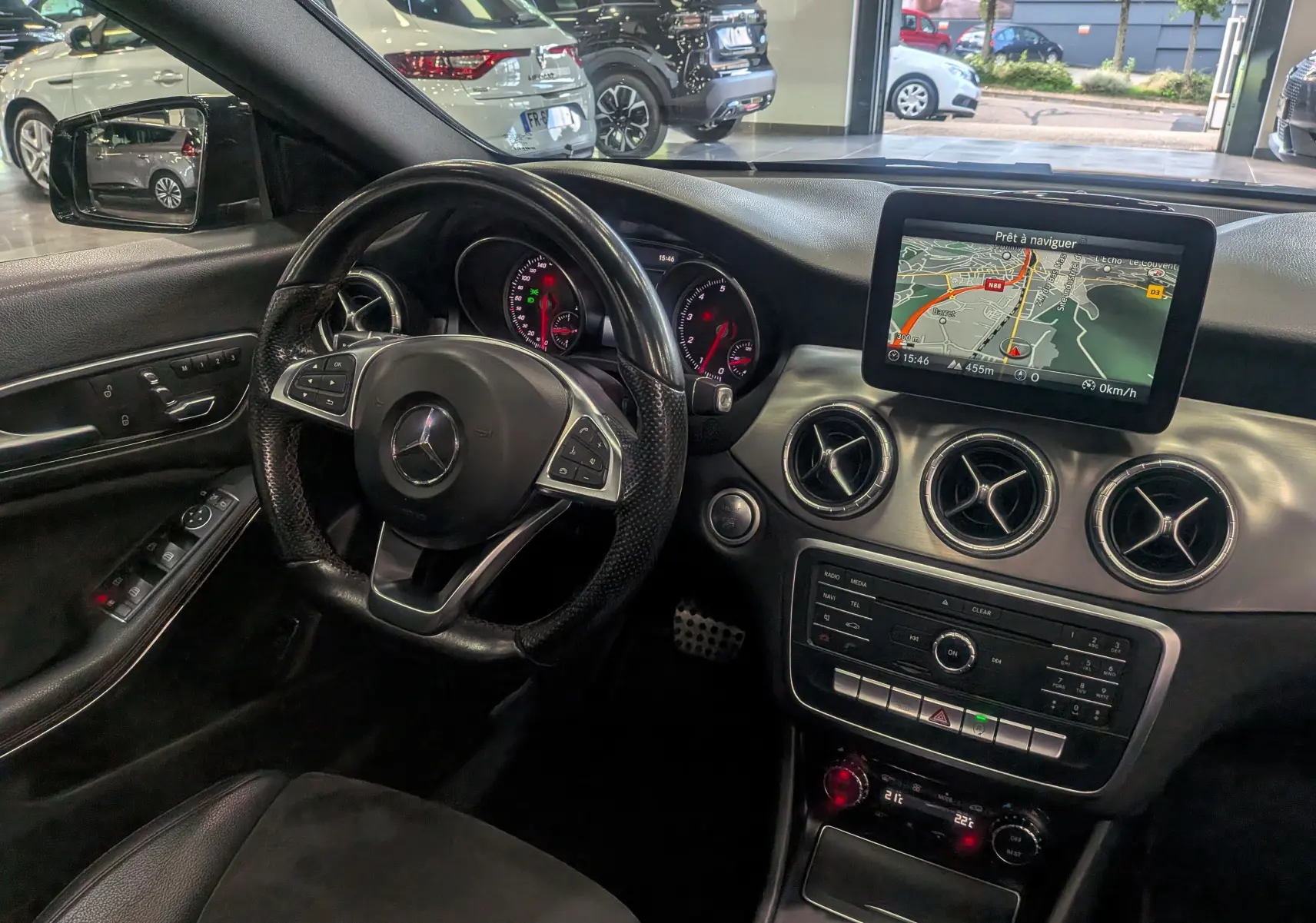 Intérieur de la Mercedes Classe CLA 200 7G-Tronic 2017, vue du poste de conduite avec écran GPS et volant cuir noir.