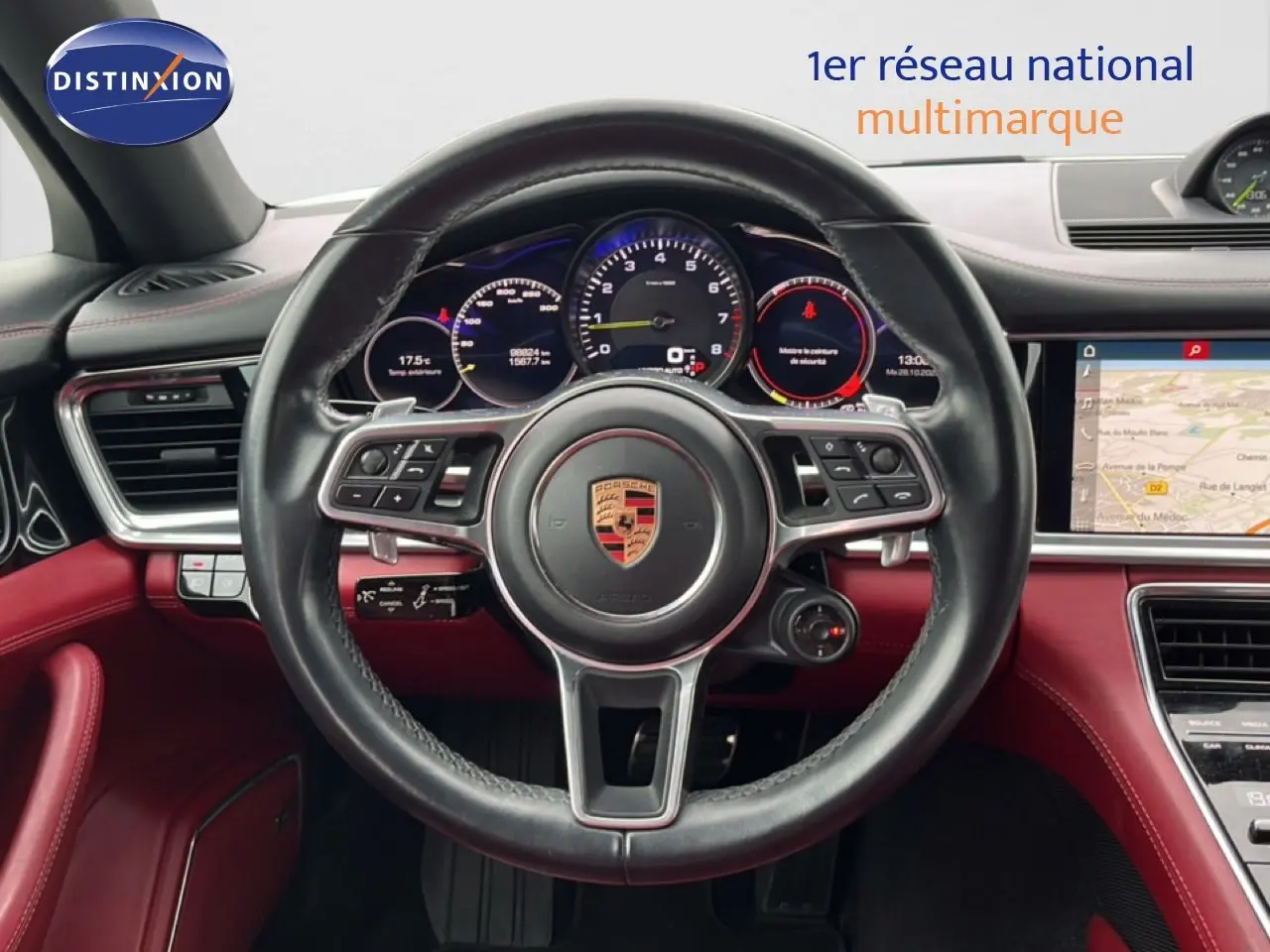 Vue centrée sur le volant cuir noir et tableau de bord rouge du Porsche Panamera 4 E-Hybrid avec affichages numériques.