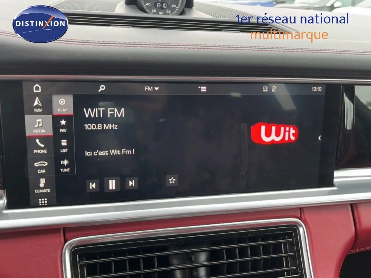Écran multimédia central affichant la radio Wit FM dans l’habitacle rouge cuir du Porsche Panamera 4 E-Hybrid.