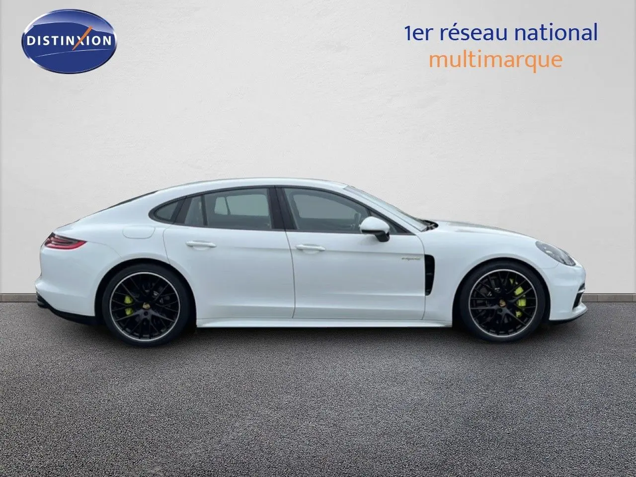 Profil droit d'une Porsche Panamera 4 E-Hybrid blanche avec jantes sport noires et étriers verts visibles.