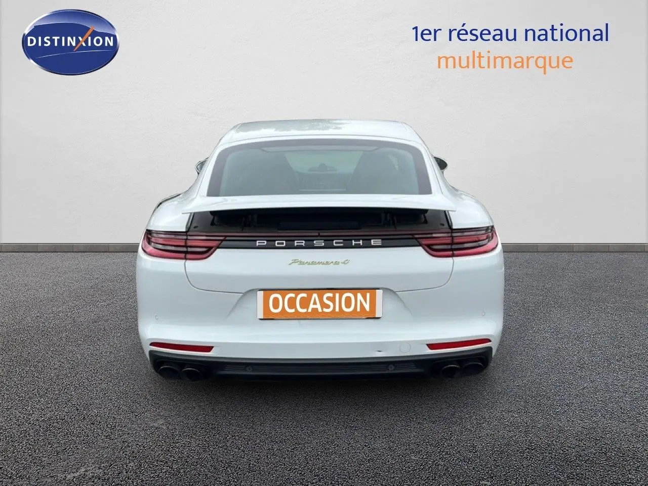 Vue arrière d'une Porsche Panamera 4 E-Hybrid blanche avec sorties d’échappement sport noires et feux LED étirés.