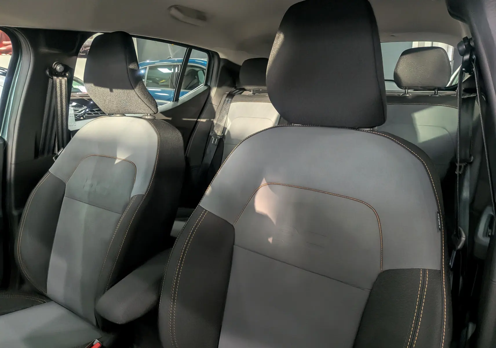 Intérieur montrant les sièges avant en tissu gris et noir avec surpiqûres contrastantes d'une Dacia Sandero Stepway 2025.