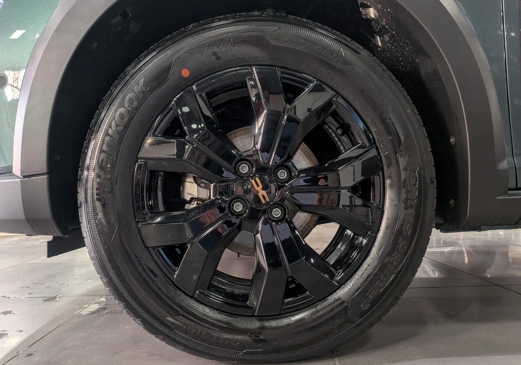 Gros plan sur la roue avant droite du Dacia Sandero Stepway TCe 110 Vert Cèdre avec jante noire brillante et logo central.