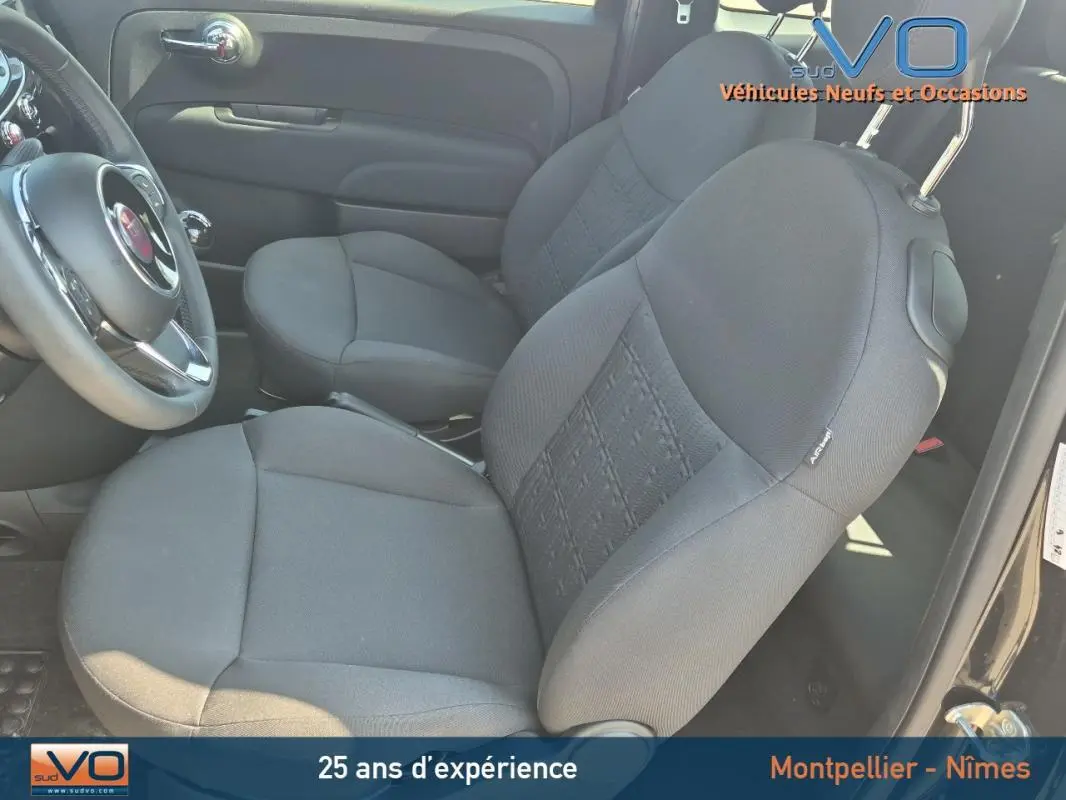 Vue intérieure côté conducteur de la FIAT 500C noire 2024, mettant en valeur les sièges en tissu et le volant.