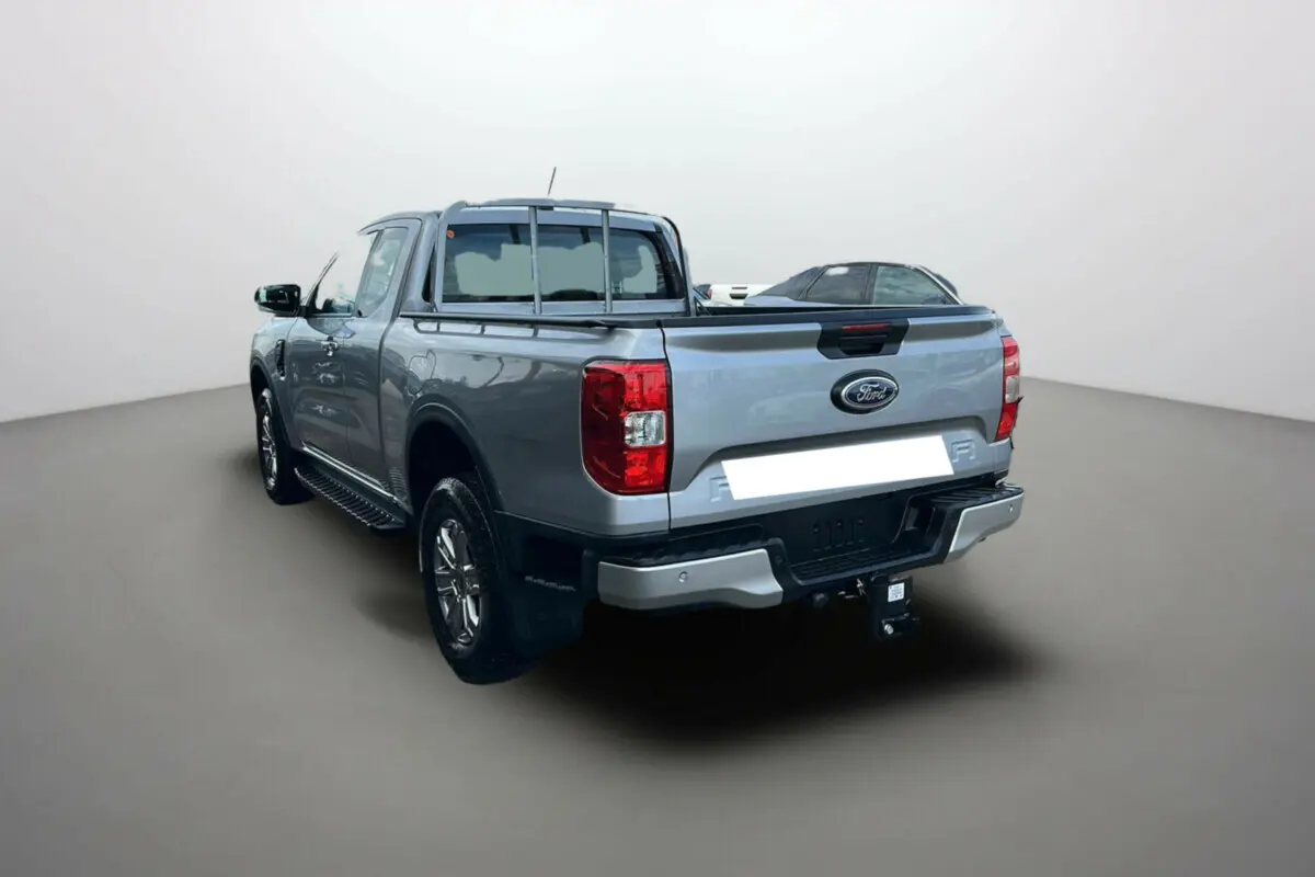 Ford Ranger gris iconic en 3/4 arrière droit, avec attelage et marchepieds latéraux visibles.