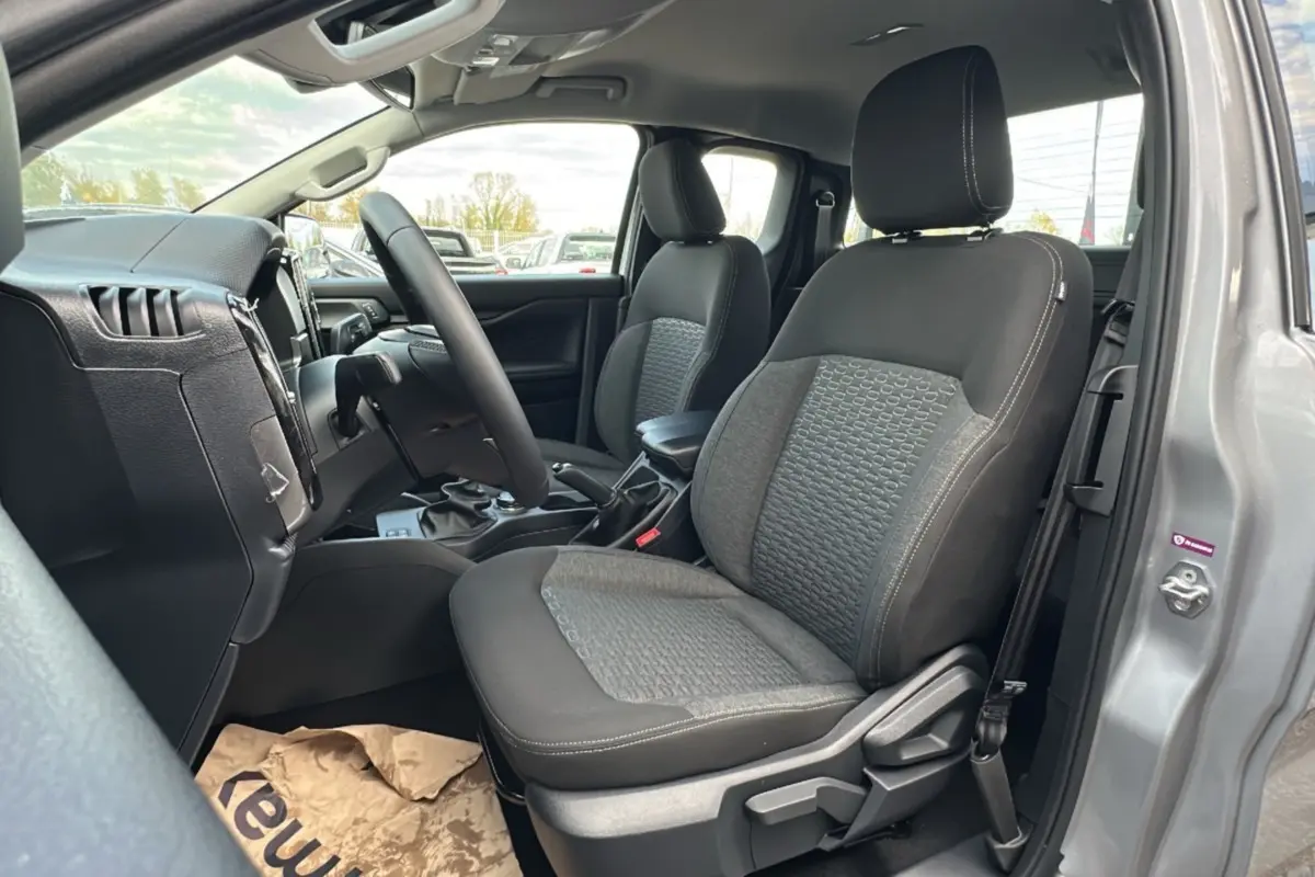 Vue intérieure côté conducteur du Ford Ranger gris iconic 2026, montrant les sièges avant en tissu et le volant multifonctions cuir.