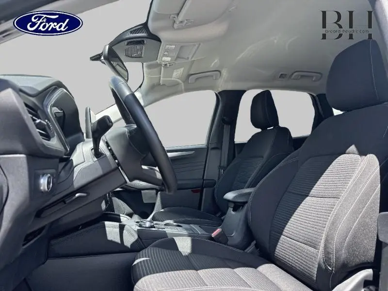 Vue intérieure côté conducteur du Ford Kuga 1.5 EcoBlue 2022, sièges sport tissu noir et volant cuir multifonction.
