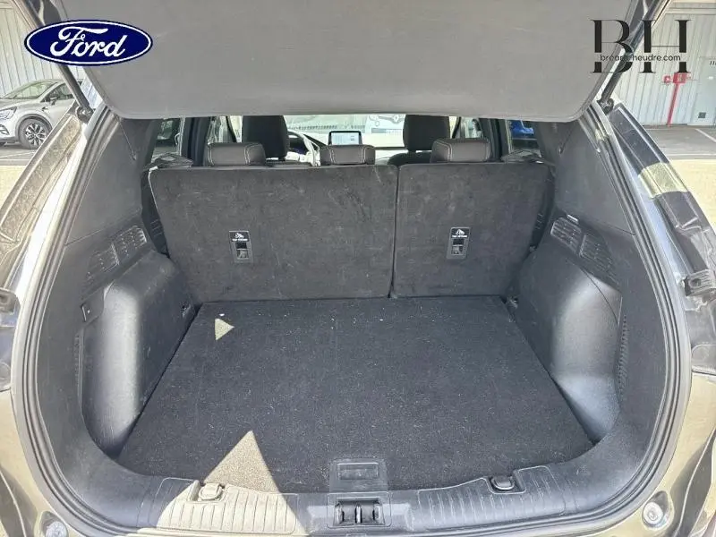 Coffre ouvert vu de l'arrière d'un Ford Kuga gris Magnetic 2022, banquette arrière en position verticale.