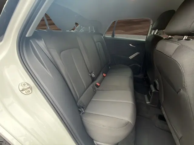 Vue intérieure arrière droite de l’Audi Q2 blanc 30 TDI 116 Design, montrant la banquette 3 places en tissu gris.