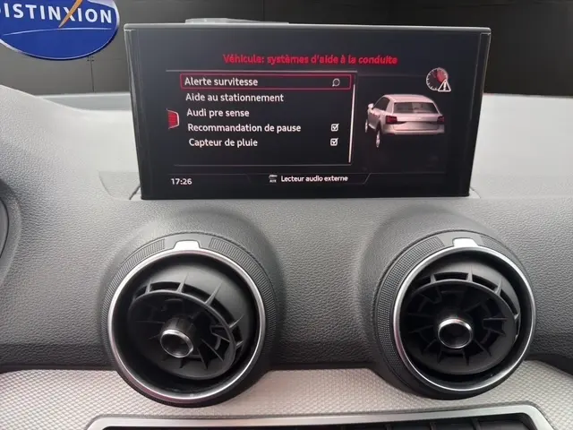 Écran central tactile de l'Audi Q2 30 TDI 116 Design 2021 montrant les aides à la conduite, avec aérateurs ronds en dessous.