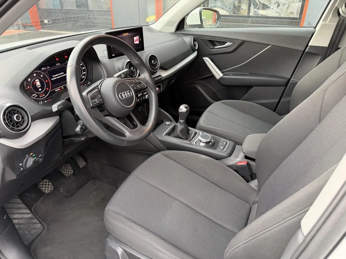 Gros plan sur la roue avant gauche d’un Audi Q2 blanc 2021 avec jante en alliage au design moderne.