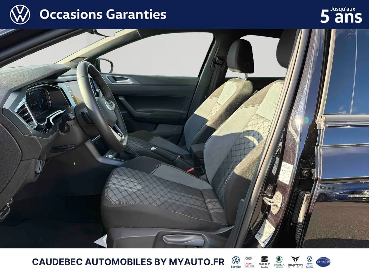 Vue intérieure côté conducteur de la Volkswagen Polo noire intense nacrée, mettant en valeur les sièges avant et le tableau de bord.