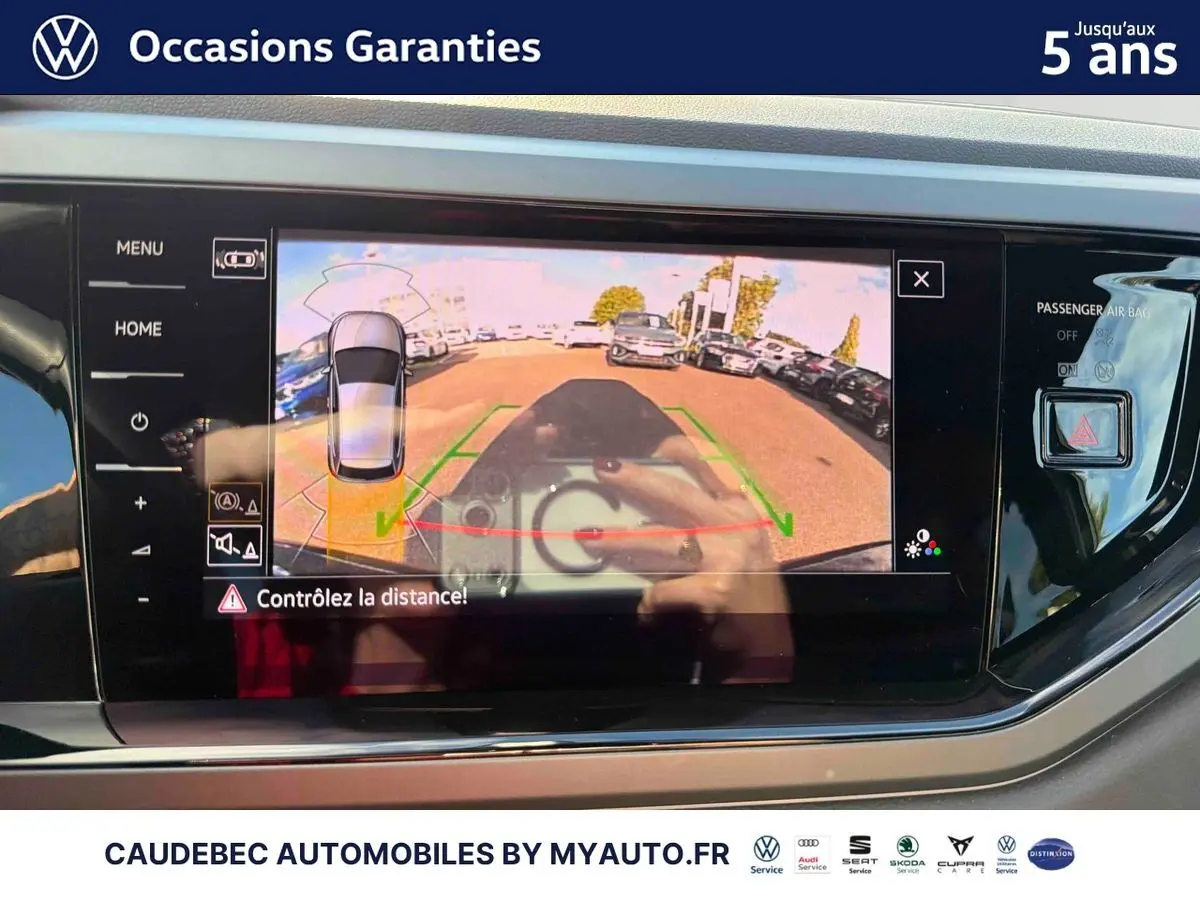 Écran tactile intérieur montrant la caméra de recul d'une Volkswagen Polo noire intense nacrée, vue arrière en stationnement.