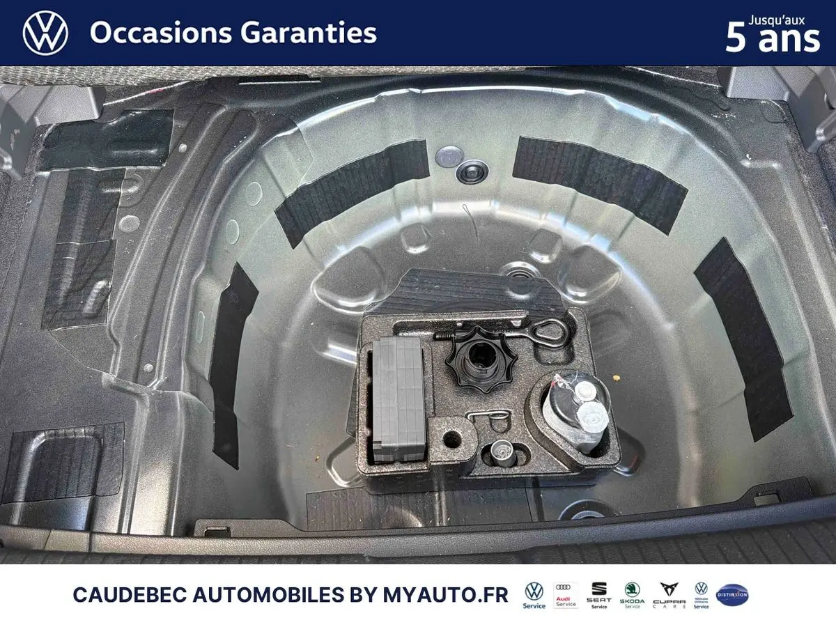 Vue plongeante sur le coffre de la Volkswagen Polo noire intense nacrée, montrant le rangement sous plancher avec outils.