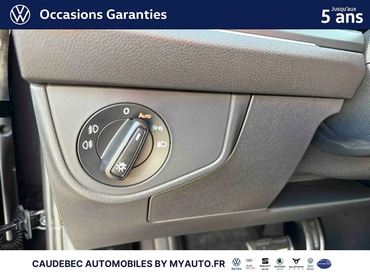 Détail du bouton de commande des phares sur tableau de bord gris foncé d’une Volkswagen Polo noire.