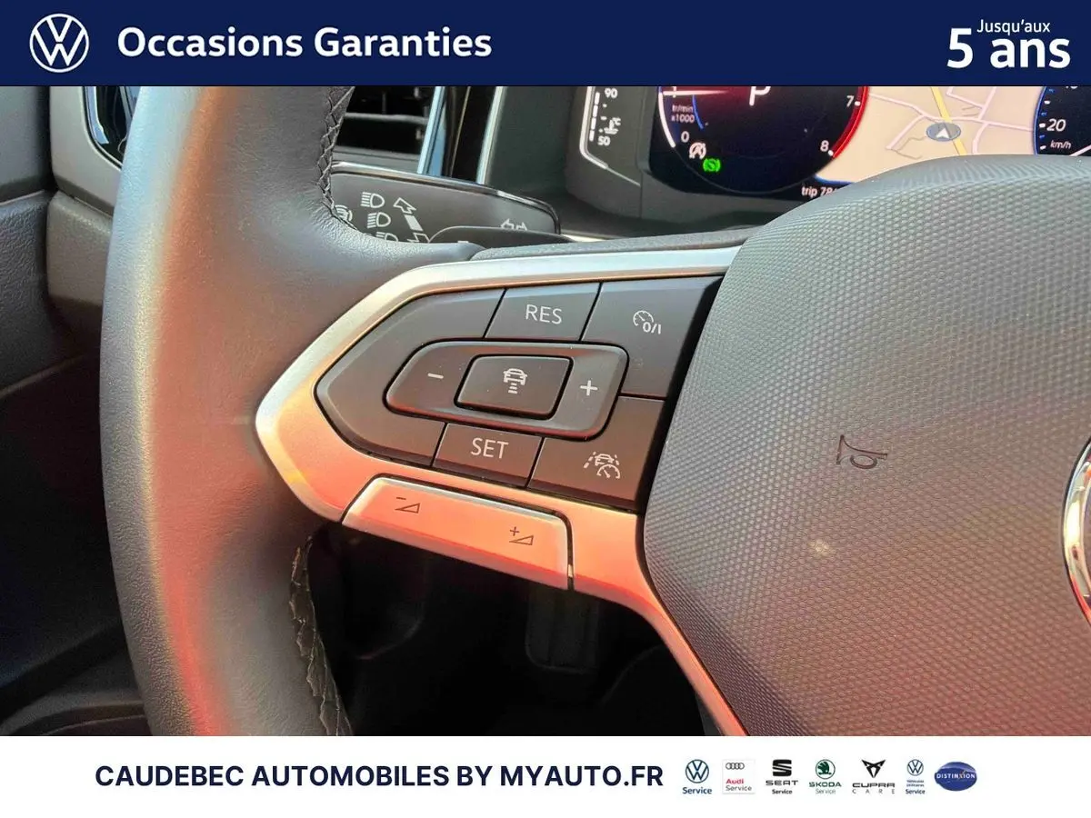 Gros plan sur les commandes du volant cuir de la Volkswagen Polo noire, mettant en valeur les boutons du régulateur de vitesse.