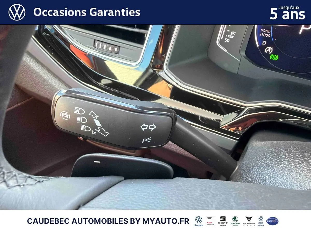 Gros plan sur la manette de clignotants noire et le tableau de bord digital de la Volkswagen Polo noire intense nacrée.