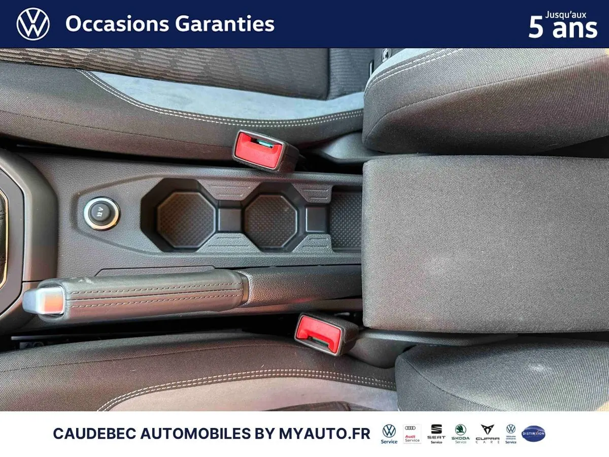 Vue rapprochée de la console centrale avec frein à main manuel et porte-gobelets de la Volkswagen Polo noire intense nacrée.