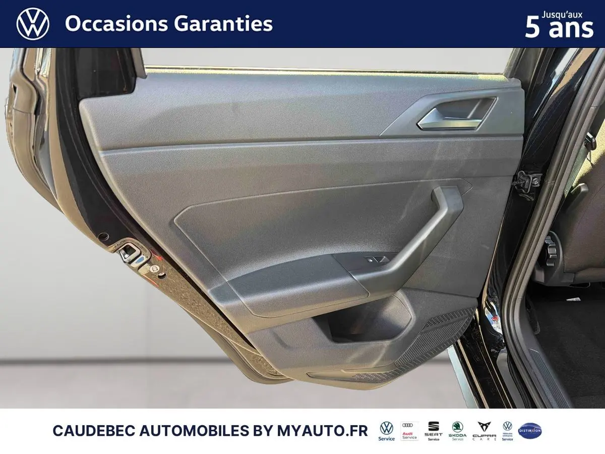 Vue rapprochée de la porte arrière gauche d'une Volkswagen Polo noire intense nacrée, montrant la garniture intérieure grise.