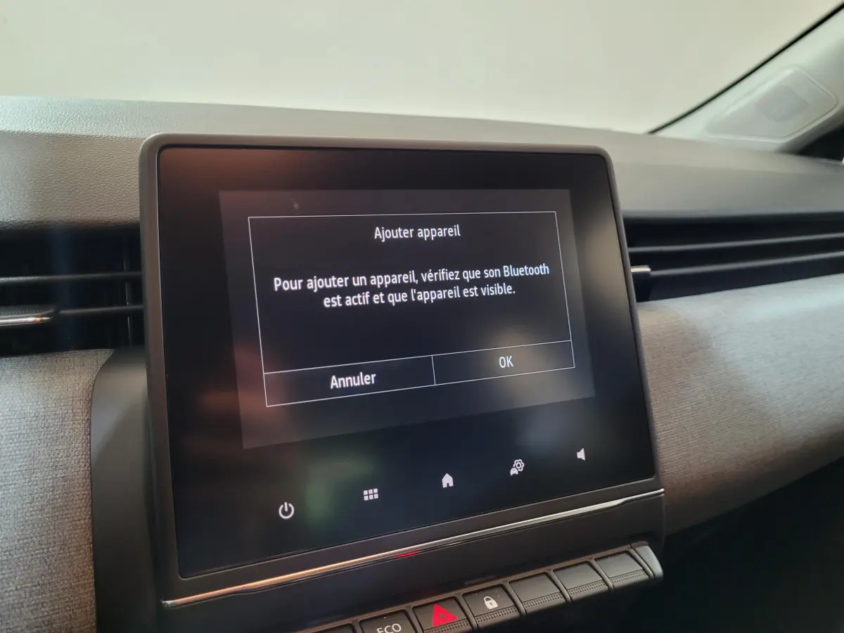 Écran tactile central affichant un message Bluetooth dans l'habitacle clair d'une Renault Clio gris foncé.