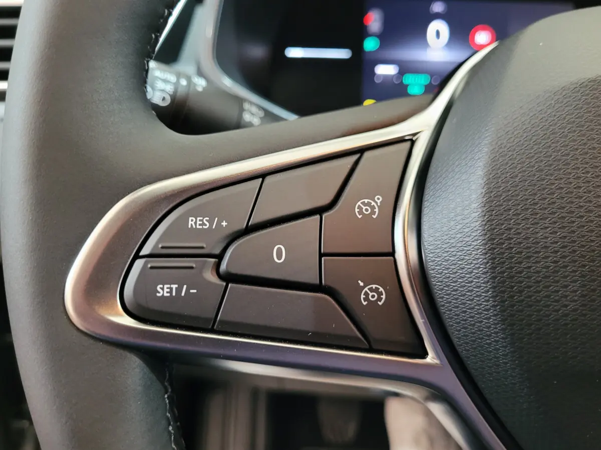 Gros plan sur les commandes de régulateur de vitesse au volant cuir de la Renault Clio gris foncé Evolution Blue dCi 100.