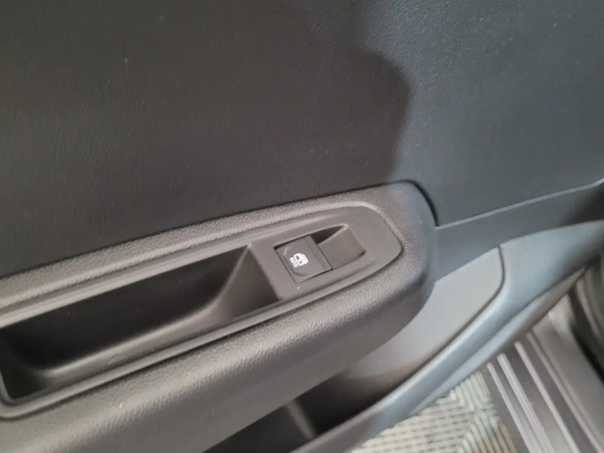 Bouton de commande de lève-vitre sur la portière côté gauche d'une Renault Clio gris foncé, vue intérieure rapprochée.