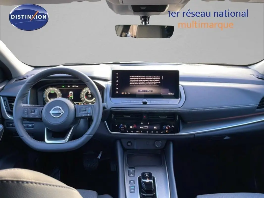 Vue intérieure frontale du tableau de bord du Nissan Qashqai gris 2025 avec écran tactile et volant cuir.