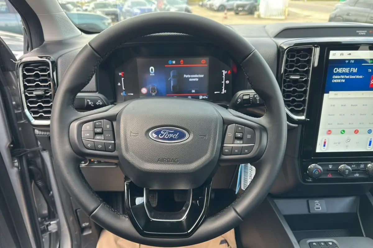 Vue rapprochée du volant cuir multifonctions du Ford Ranger gris iconic avec tableau de bord digital et écran tactile central.