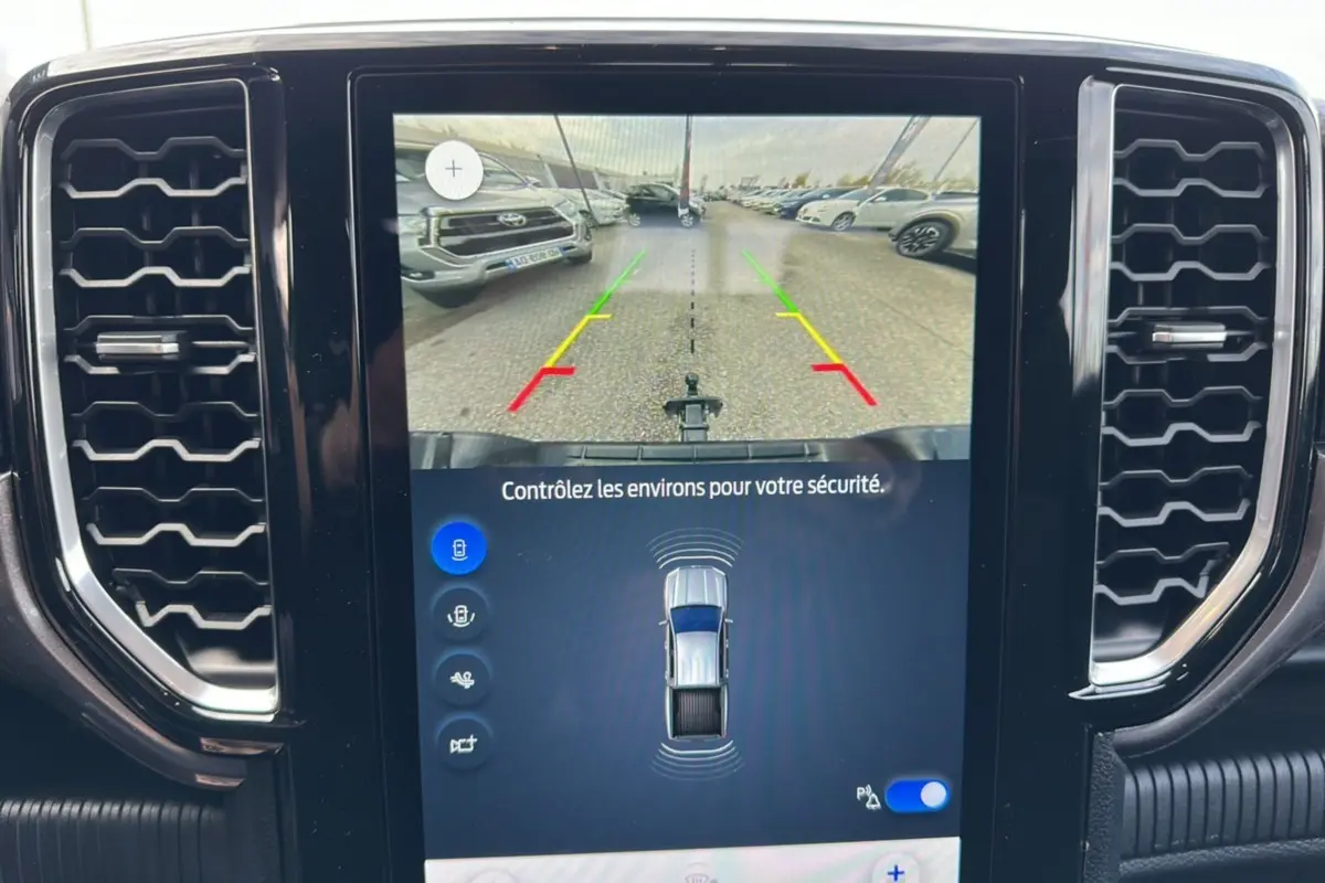 Écran tactile central du Ford Ranger gris montrant la caméra de recul et les capteurs de stationnement.