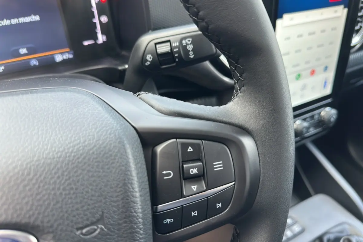 Gros plan sur le volant cuir multifonctions du Ford Ranger 2026 avec commandes intégrées et écran tactile en arrière-plan.