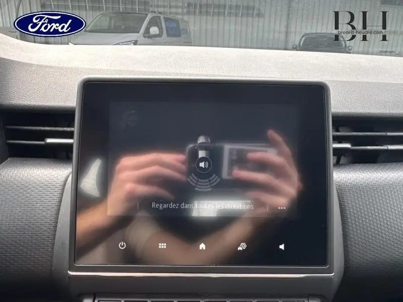 Écran tactile central du tableau de bord de la Renault Clio gris platine, avec reflets visibles sur l'écran.
