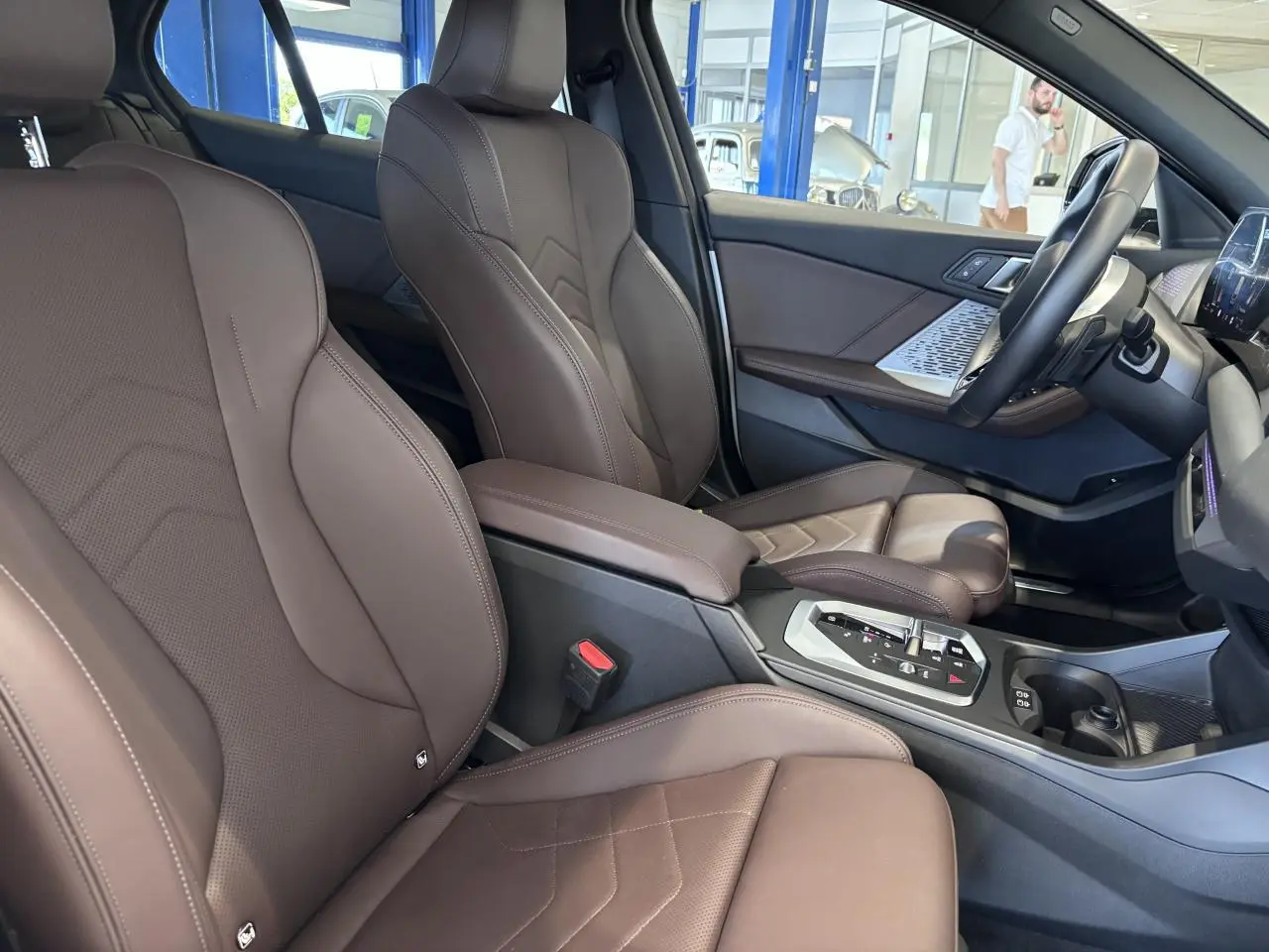 Intérieur de la BMW Série 1 120d M Sport 2025 vu côté droit, sièges en cuir marron et console centrale moderne.