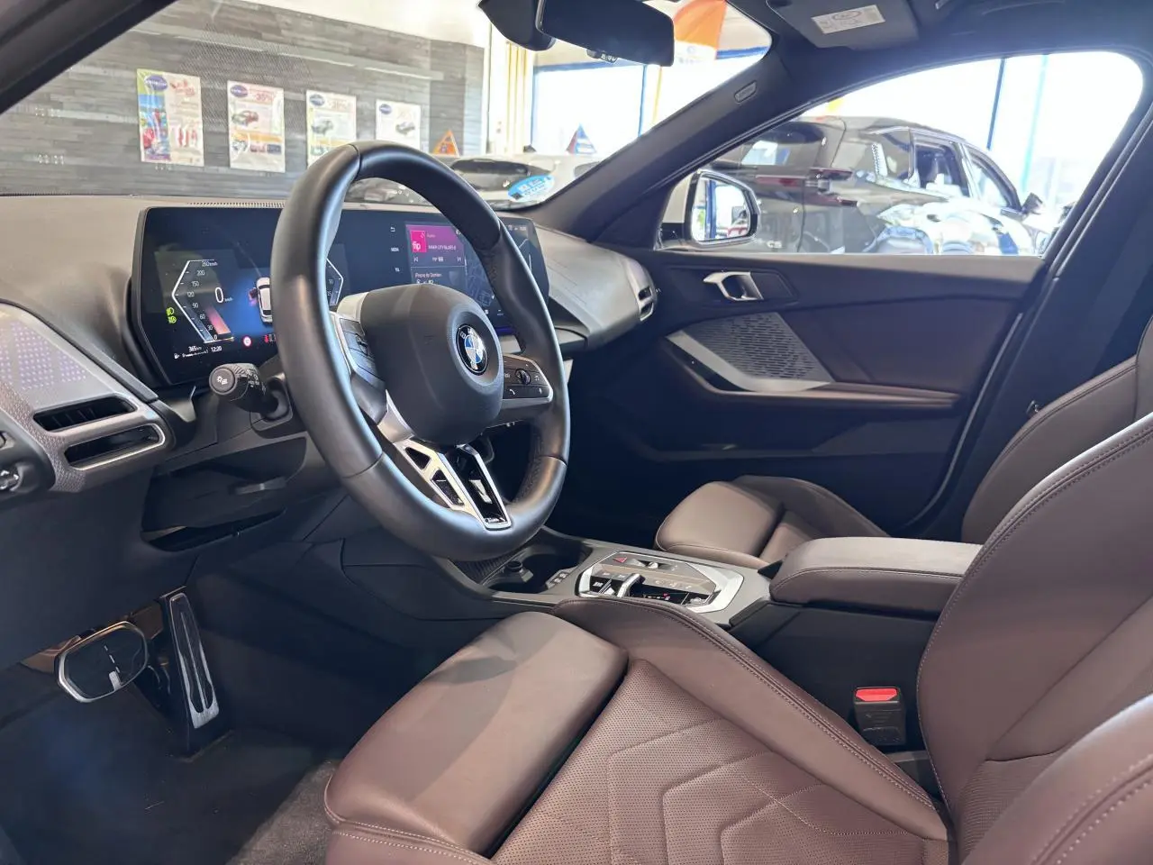 Vue intérieure côté conducteur de la BMW Série 1 120d M Sport 2025 avec tableau de bord numérique et sellerie marron.