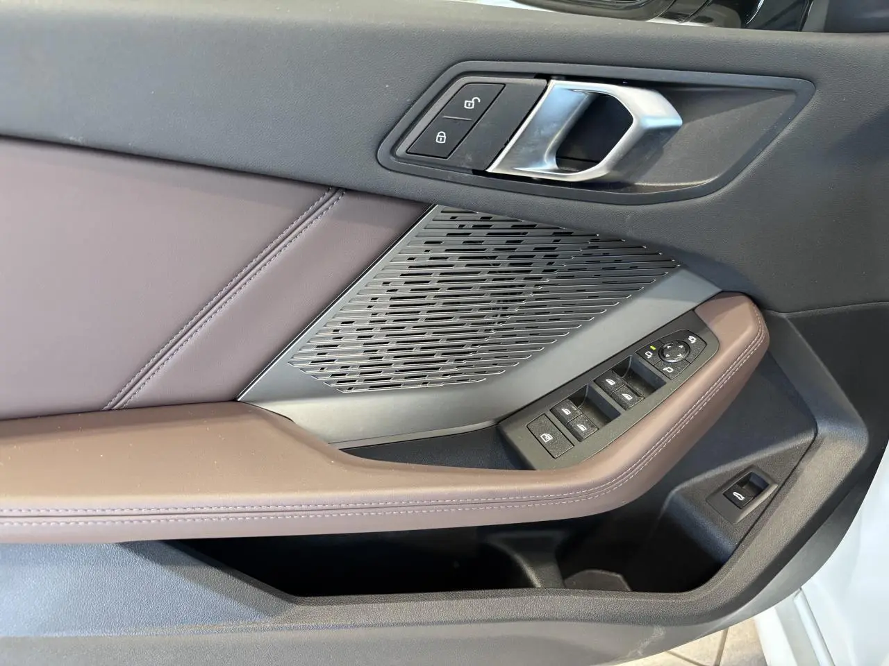Détail de la porte côté conducteur de la BMW Série 1 120d M Sport 2025 blanche, avec commandes et garniture marron.