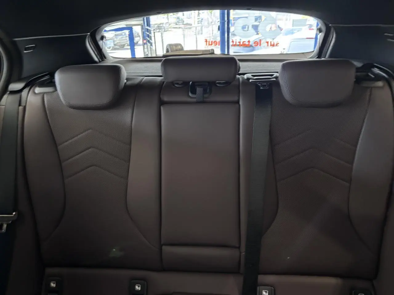 Vue intérieure des sièges arrière en cuir noir de la BMW Série 1 120d M Sport 2025, avec appuie-têtes et ceinture de sécurité.