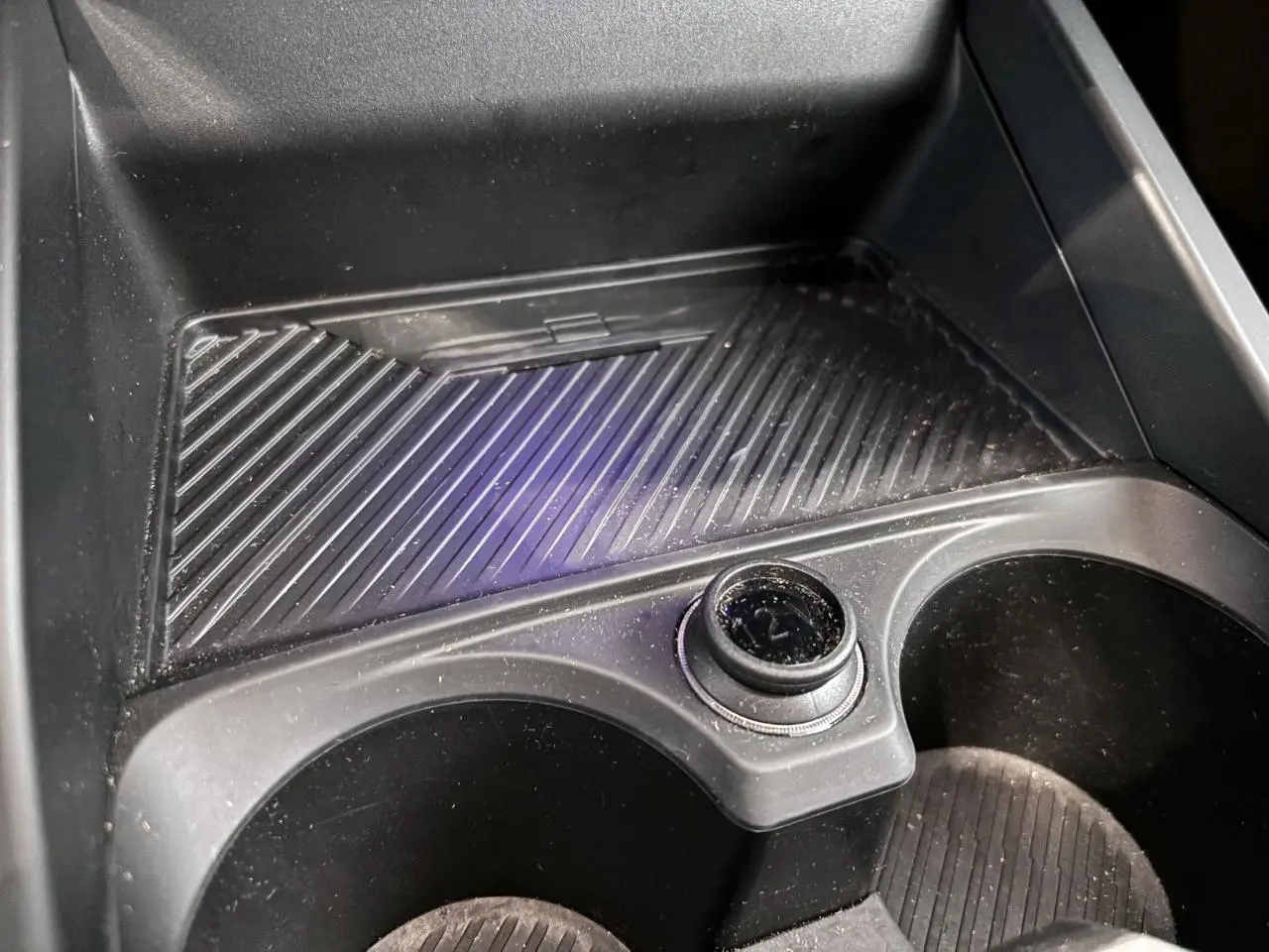 Gros plan sur le porte-gobelets intérieur noir de la BMW Série 1 120d M Sport 2025, avec prise 12V visible.
