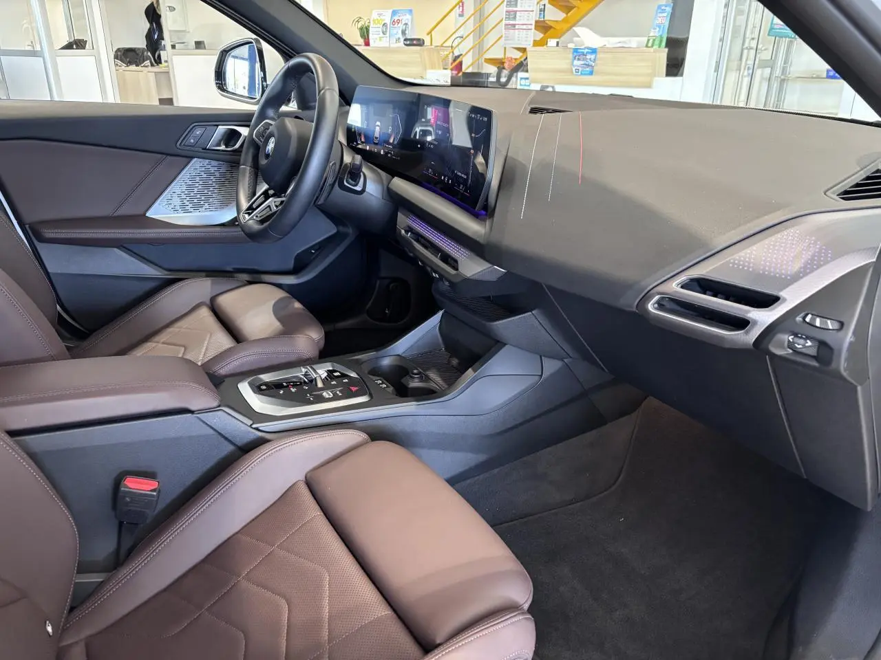 Vue intérieure côté passager de la BMW Série 1 120d M Sport 2025, sièges marron et tableau de bord moderne noir.