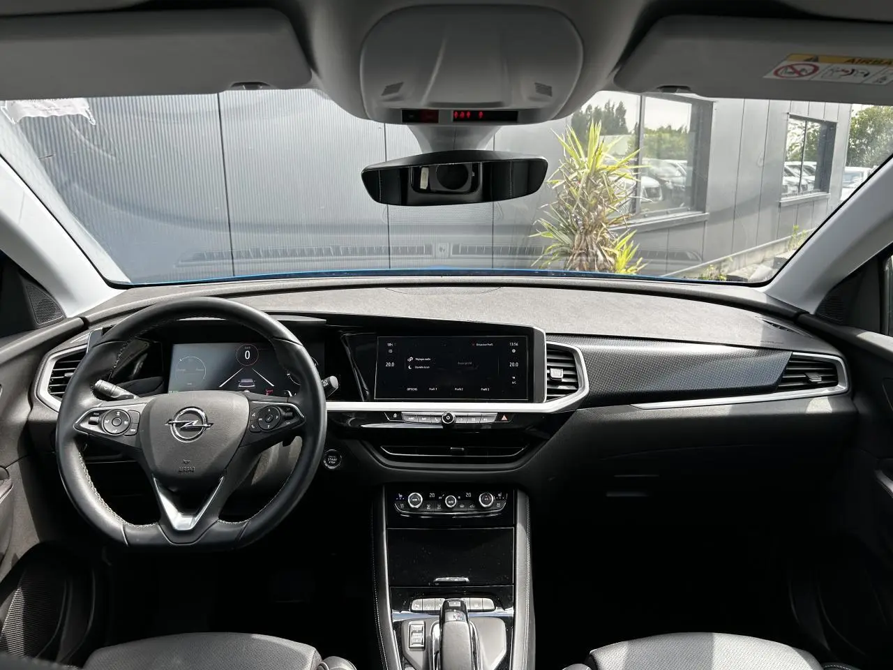 Vue intérieure avant de l'Opel Grandland bleu Vertigo, tableau de bord moderne avec écran tactile et volant cuir multifonction.