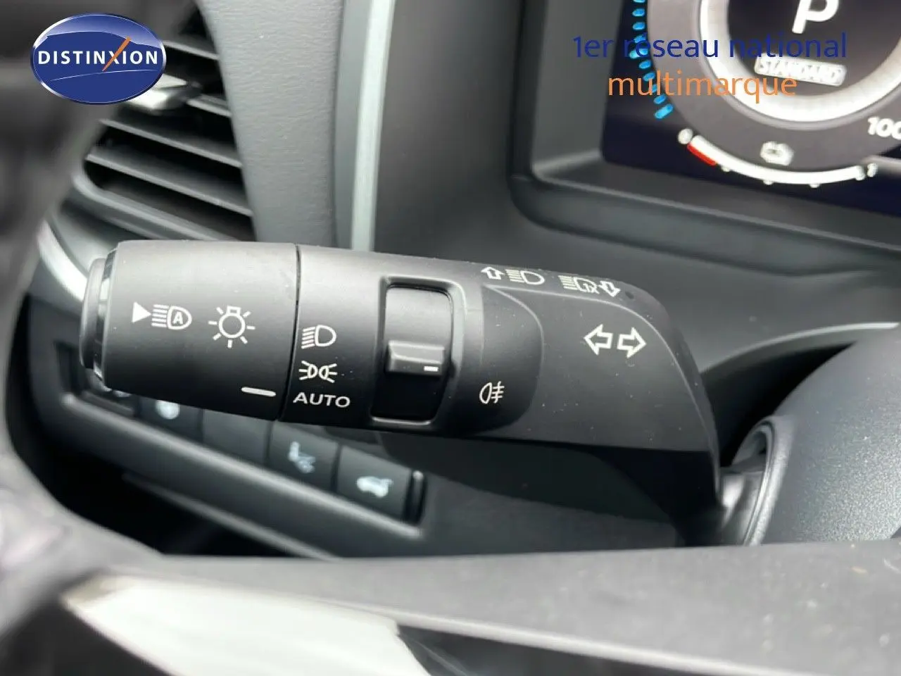 Gros plan sur la commande des phares et clignotants du Nissan Qashqai blanc nacré, intérieur noir visible.