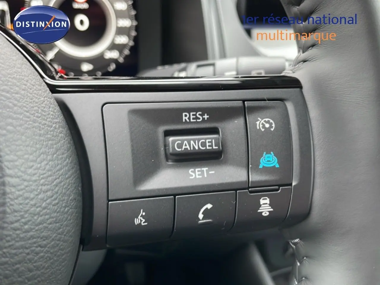 Gros plan sur les commandes au volant en cuir gris du Nissan Qashqai blanc nacré 2025, avec régulateur de vitesse et assistance.