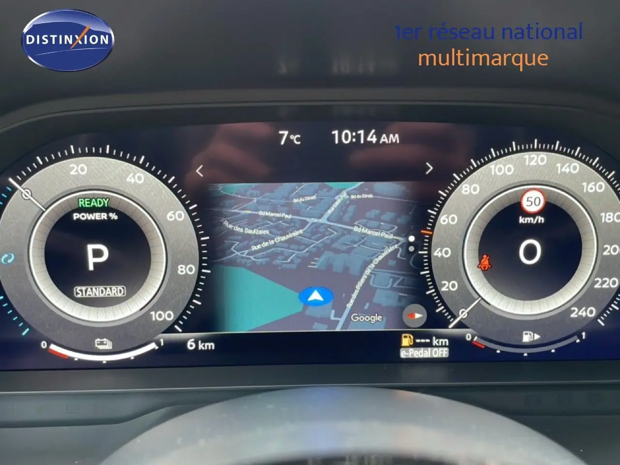 Tableau de bord numérique du Nissan Qashqai blanc nacré, affichant la vitesse, la navigation et l'état du véhicule.
